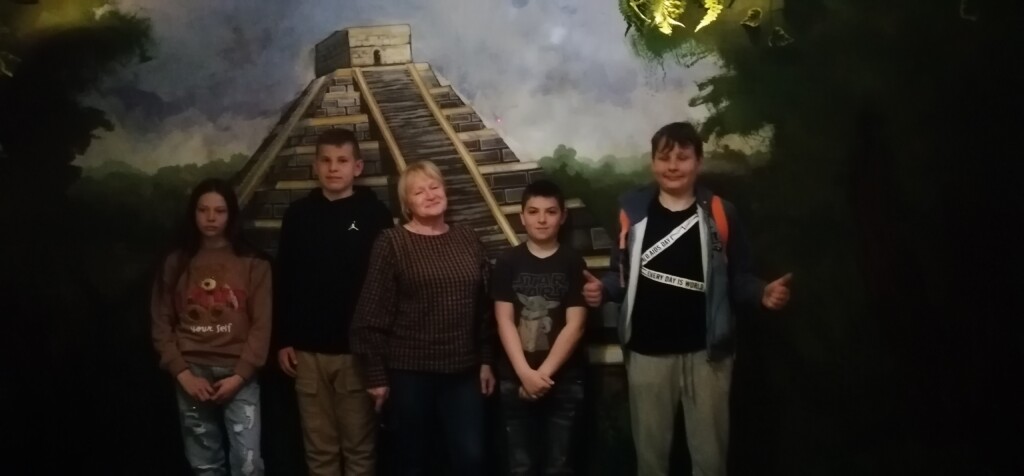 Czwórka uczniów z opiekunem stojący na tle piramidy