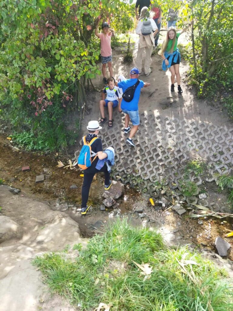 uczniowie przechodzący przez strumyk